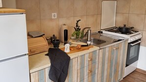 A compact kitchen with wooden cabinets, a stove, a sink, and a refrigerator. - Apartment Milan (Vrboska)