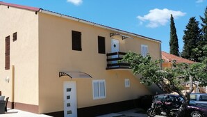 A two-story building with a beige facade, white shutters, and a red roof. - Apartment Milan (Vrboska)
