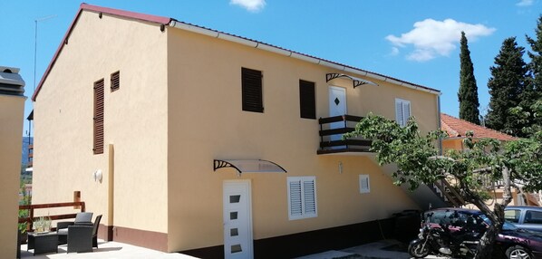Um edifício de dois andares com fachada bege, portas brancas e persianas marrons.