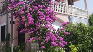A building with a balcony and a tree with purple flowers. - Apartments Plava Plaza Daniela (Vodice)