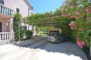 A residential street with a parked car, a house with a balcony, and a garage. - Apartments Plava Plaza Daniela (Vodice)