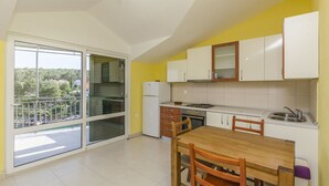 A modern kitchen with a dining area, large windows, and a view of greenery. - Apartment Ivo (Basina)