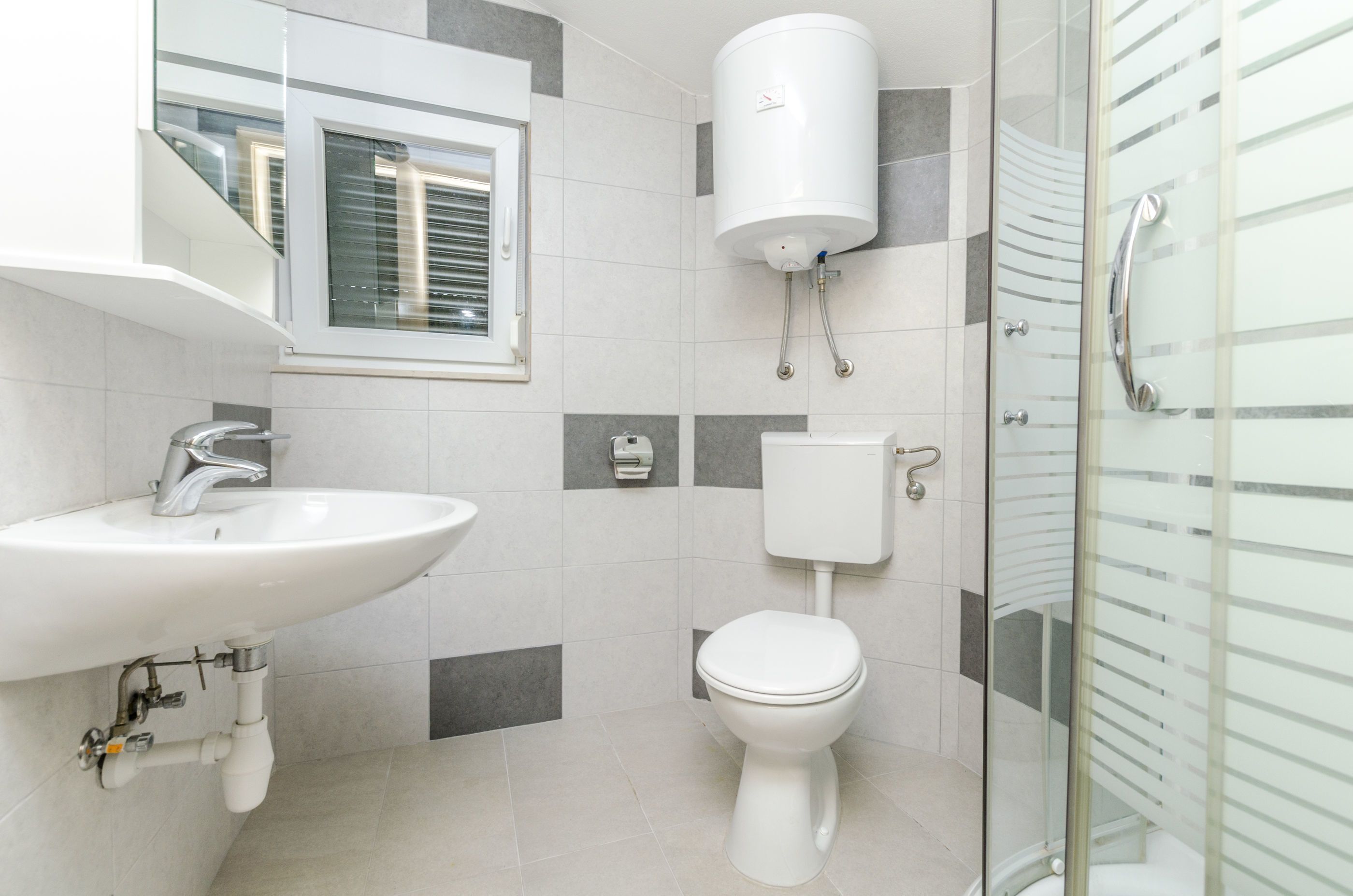 A modern bathroom with a white sink, toilet, and shower.