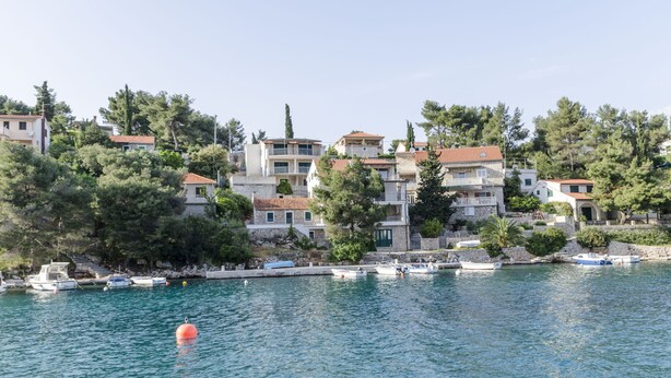 A coastal village with buildings on a hillside overlooking the sea. - Apartment Ivo (Basina)