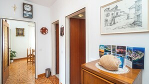 A hallway with patterned floor tiles, a wooden door, a framed artwork, and a small wooden table with a decorative object. - Apartment Luketa (Primosten)