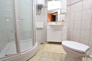 Ein modernes Badezimmer mit einer Duschkabine aus Glas, einem weißen Waschbecken mit Spiegel darüber und einer Toilette.