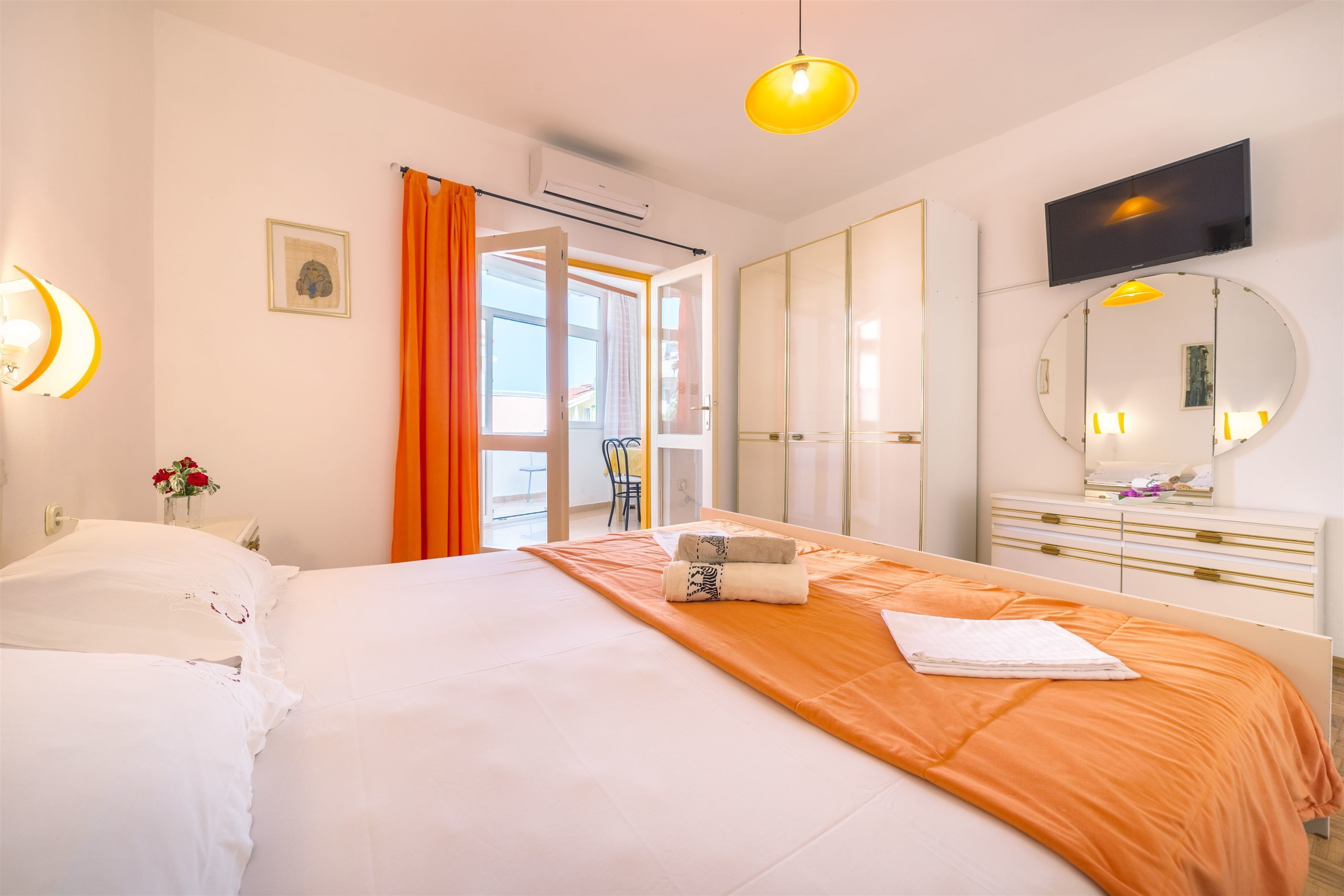 A hotel room with a bed, a large mirror, a television, and a window with curtains.