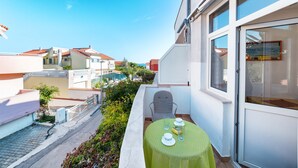 A balcony with a table set for two, overlooking a street with neighboring houses. - Apartments Zanze (Vodice)