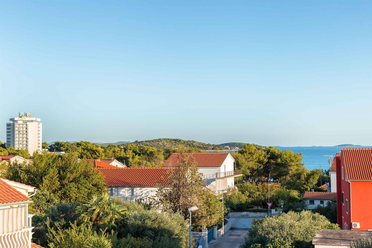 A coastal town with buildings, trees, and a clear view of the sea.