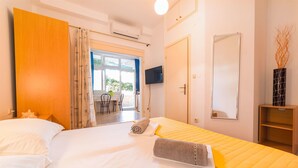 A hotel room with a bed, a TV, a door, and a view of the outside. - Apartments Zanze (Vodice)