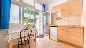 A compact kitchen with a built-in dishwasher, wooden cabinets, and a window overlooking a garden. - Apartments Zanze (Vodice)