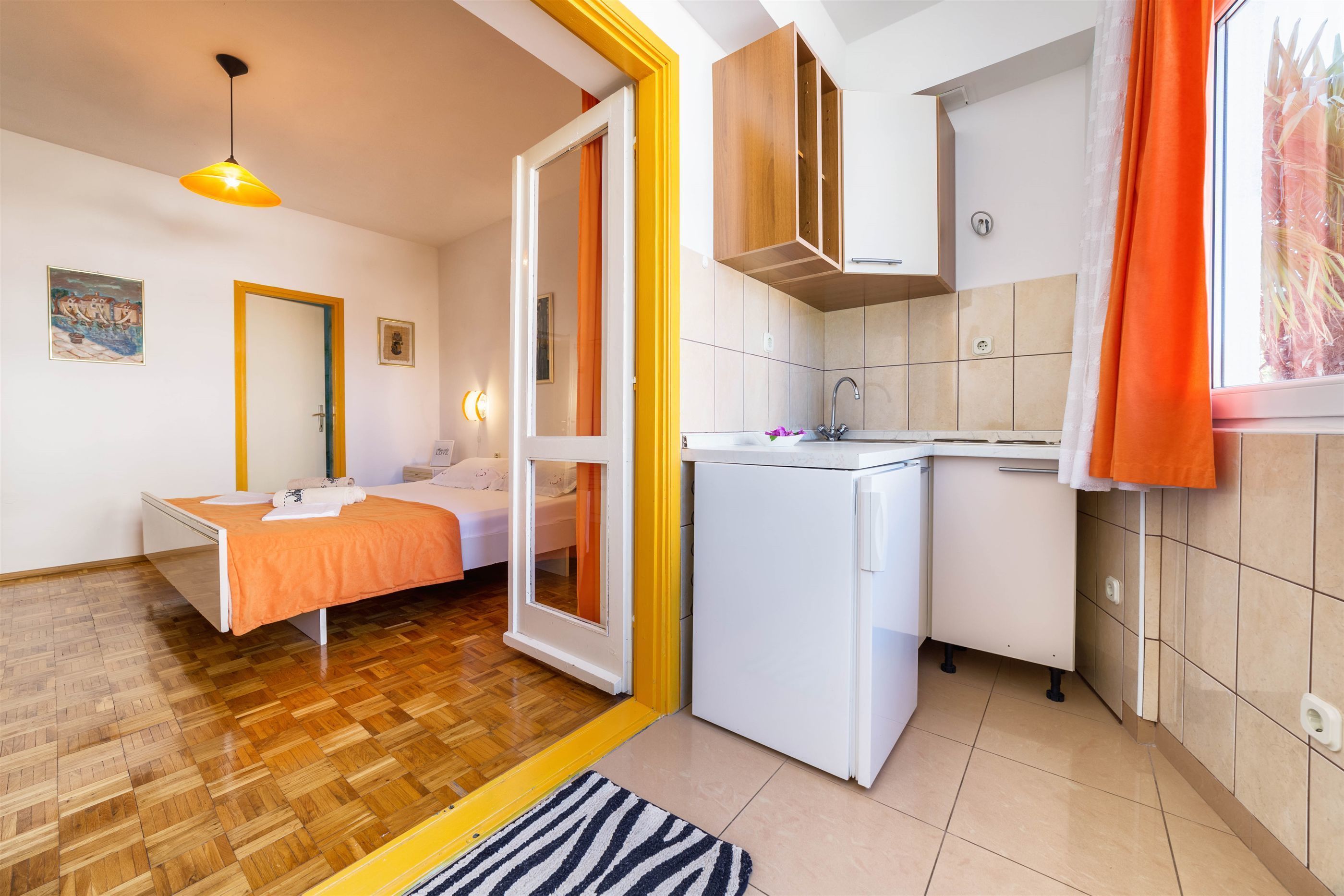 A compact room with a bed, a small kitchenette, and a bathroom.