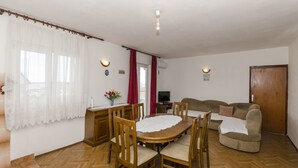 Un coin repas avec une table et des chaises en bois, un canapé et un téléviseur.