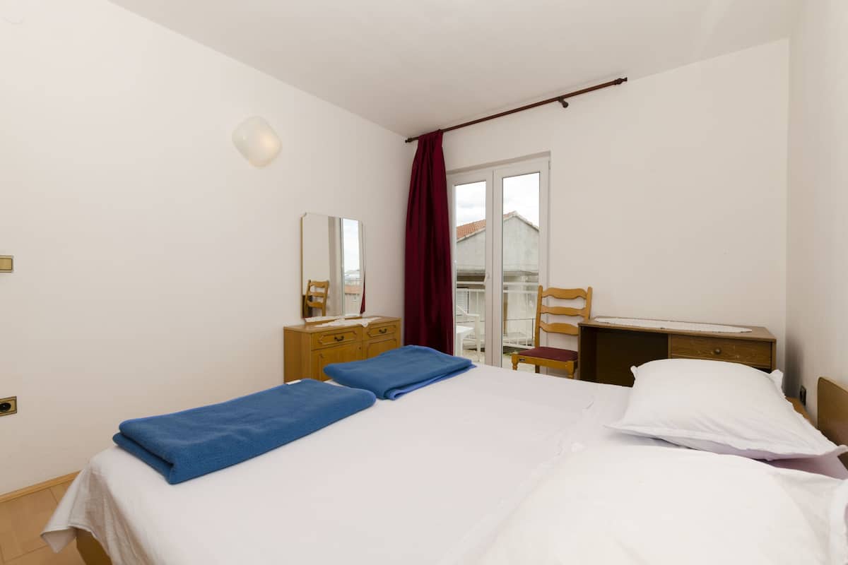 A hotel room with a bed, a desk, a chair, a wardrobe, and a window with curtains.