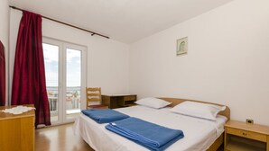 Une chambre à coucher comprenant un lit, une table de chevet, un bureau en bois et une vue sur l’extérieur grâce à une porte coulissante.