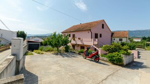 A pink two-story house with a red scooter parked in front. - Apartment Lavcevic (Vrboska)