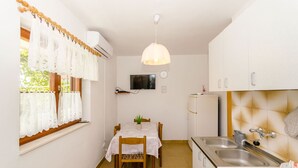 A compact kitchen with a dining table, a hanging light fixture, and a built-in oven. - Apartment Lavcevic (Vrboska)