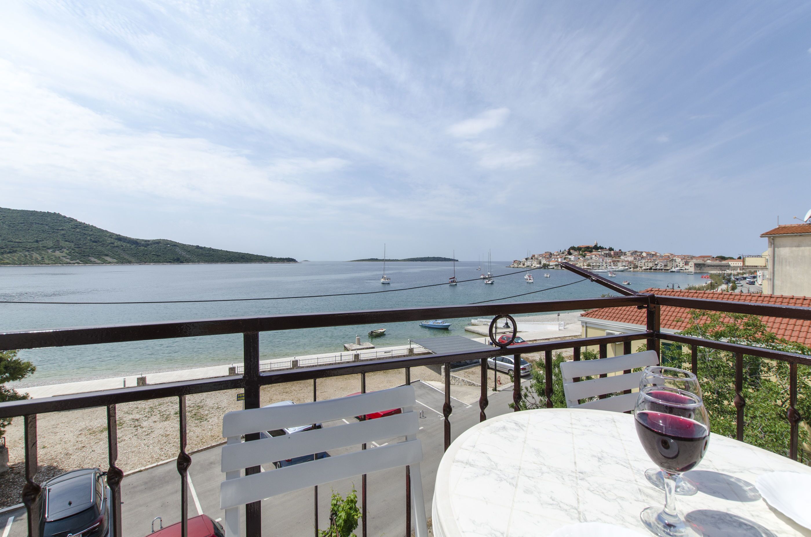 Ein Balkon mit Tisch, einem Weinglas und Blick auf das Meer und Boote.