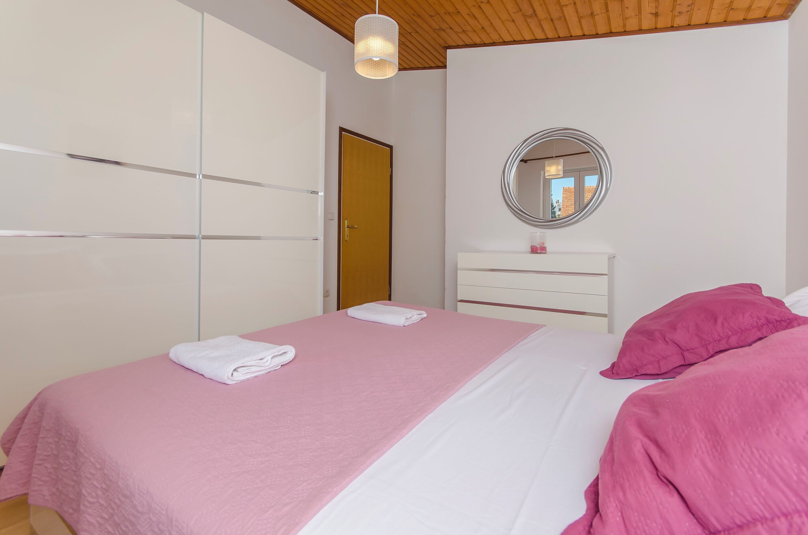 Un dormitorio con cama, armario, espejo y puerta.