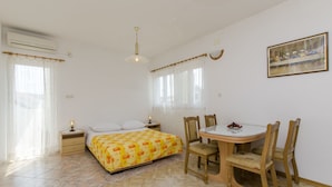 Une chambre à coucher comprenant un lit, une table de chevet, une lampe, ainsi qu’un coin repas avec une table et des chaises.