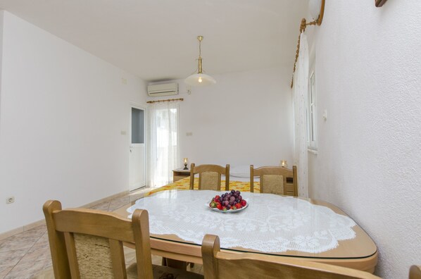 A dining area with a round table, chairs, a fruit bowl, and a ceiling light.