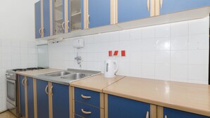 A kitchen with blue cabinets, a stainless steel sink, a kettle, and a stove. - Apartment Tome G (Primosten)