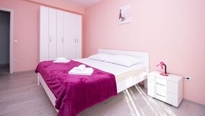 A bedroom with a bed, white wardrobe, and a nightstand with a lamp. - Apartment Brko (Primosten)