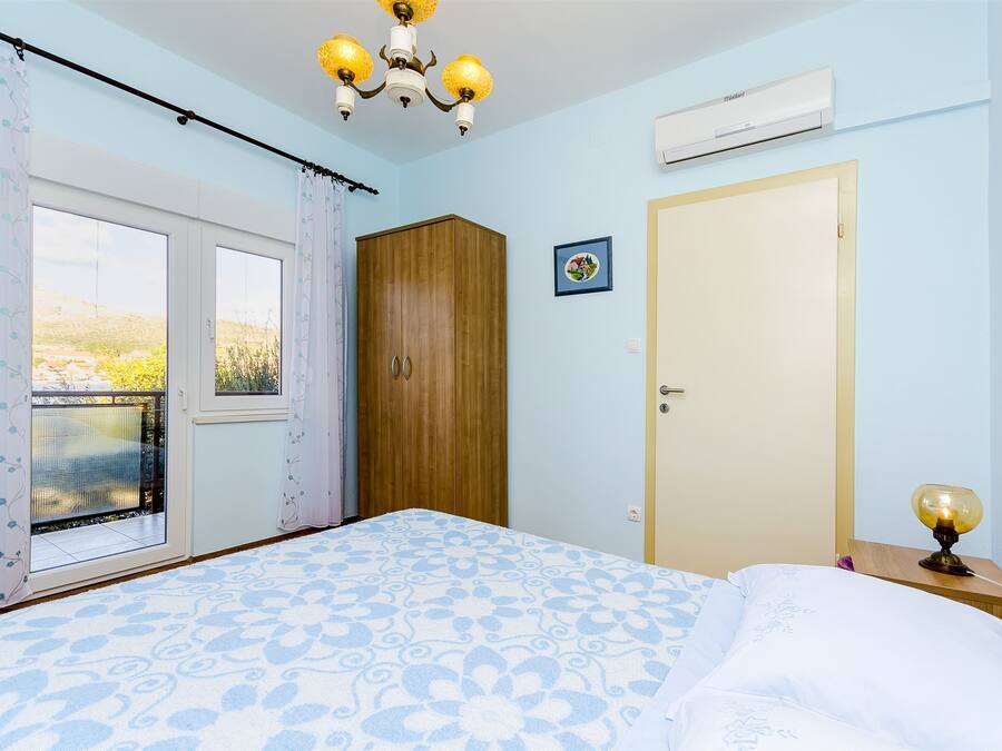 Une chambre à coucher avec un grand lit, une armoire, une porte et un appareil de climatisation.