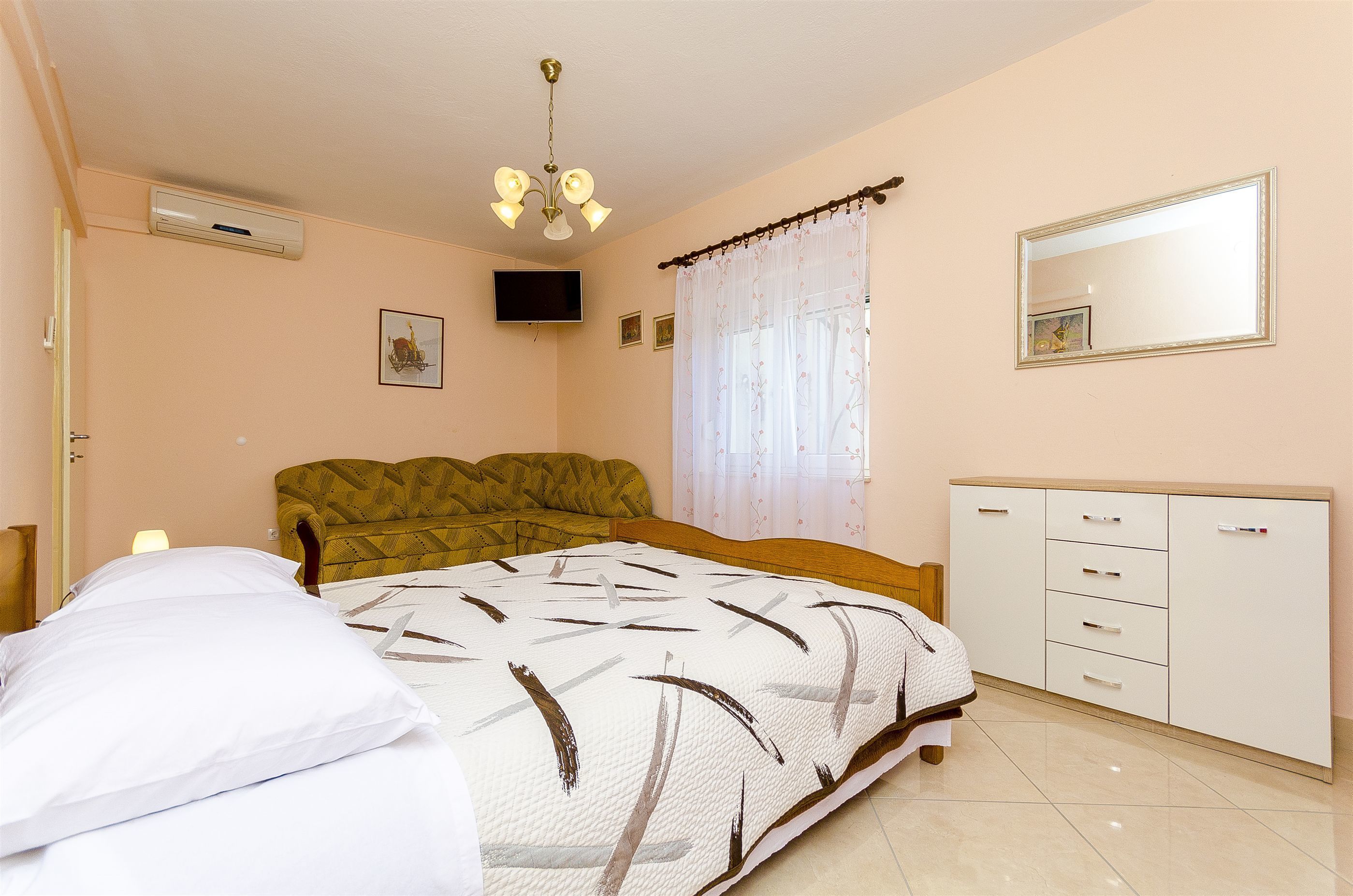 A bedroom with a bed, a bedside table, a wardrobe, a ceiling fan, and a window with curtains.