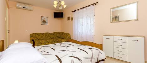A bedroom with a bed, a bedside table, a wardrobe, a ceiling fan, and a window with curtains.