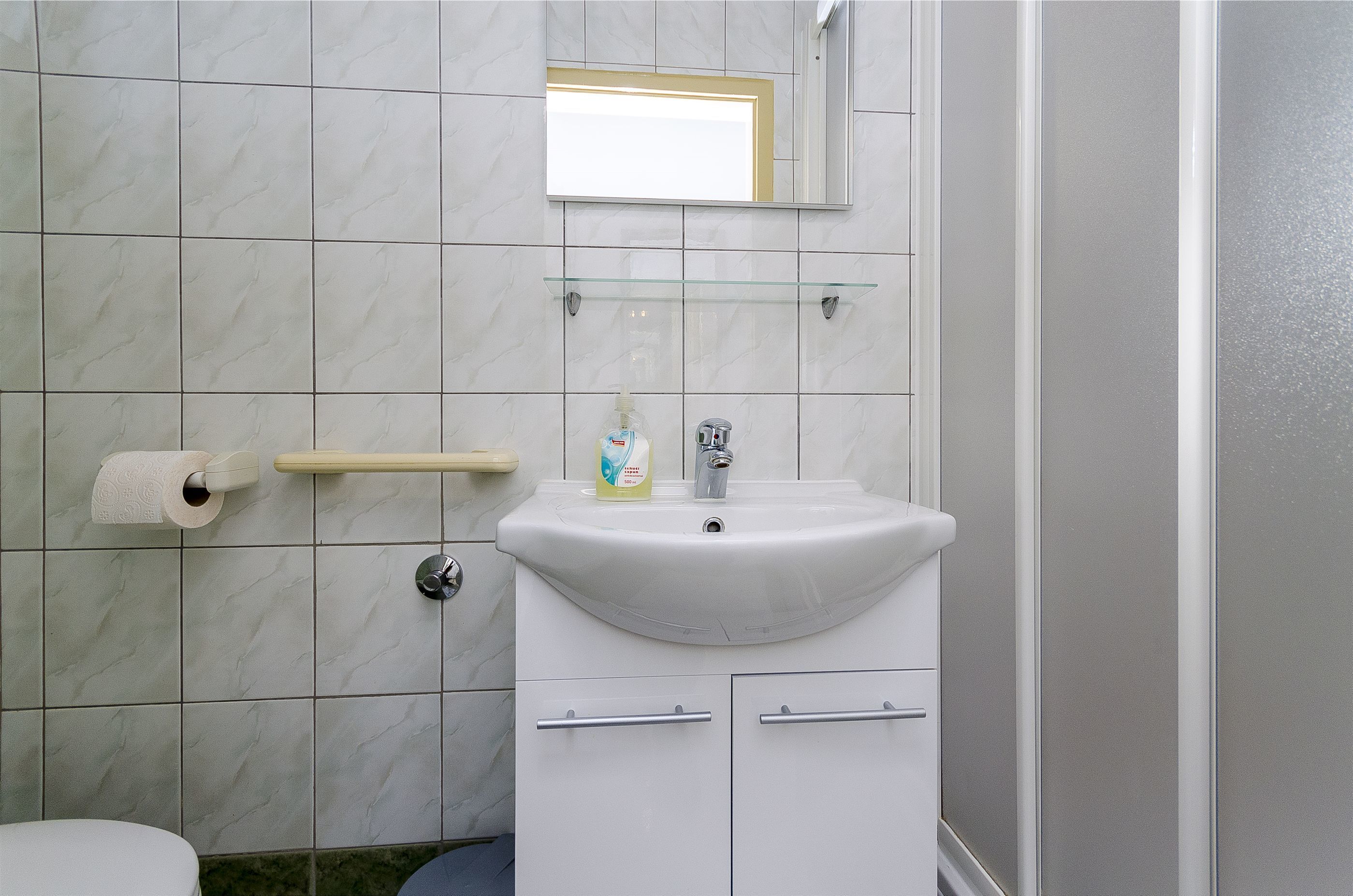 A bathroom with a white sink, a mirror above it, and a toilet to the left.