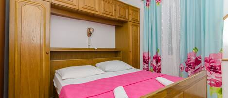 Una camera da letto con un letto di legno, una testiera bianca e una coperta rosa.