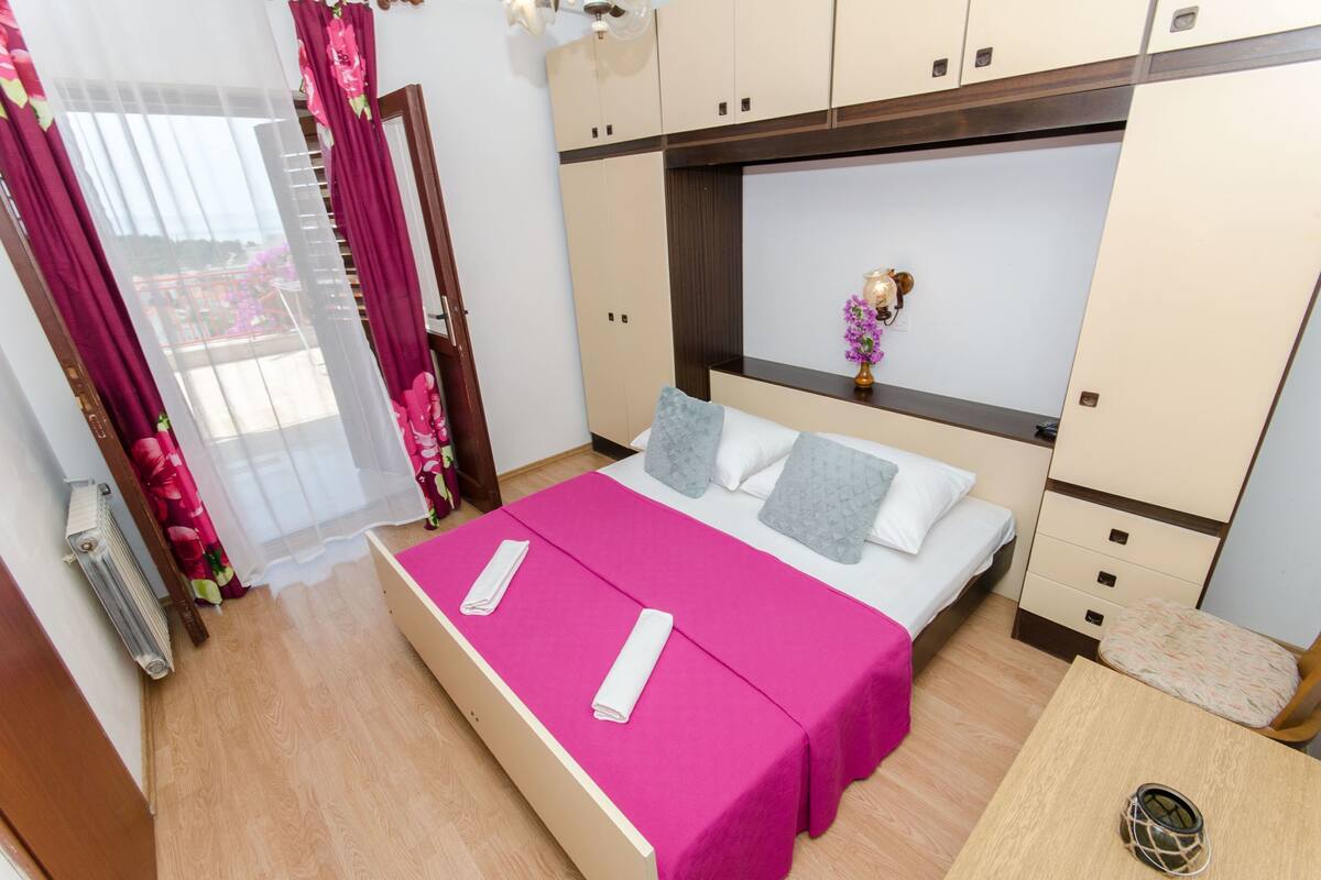 Ein ordentlich eingerichtetes Schlafzimmer mit Bett, Nachttischen und einem Kleiderschrank.