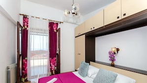 Una camera d'albergo con un letto, una finestra con tende, un termosifone e un lampadario a parete.