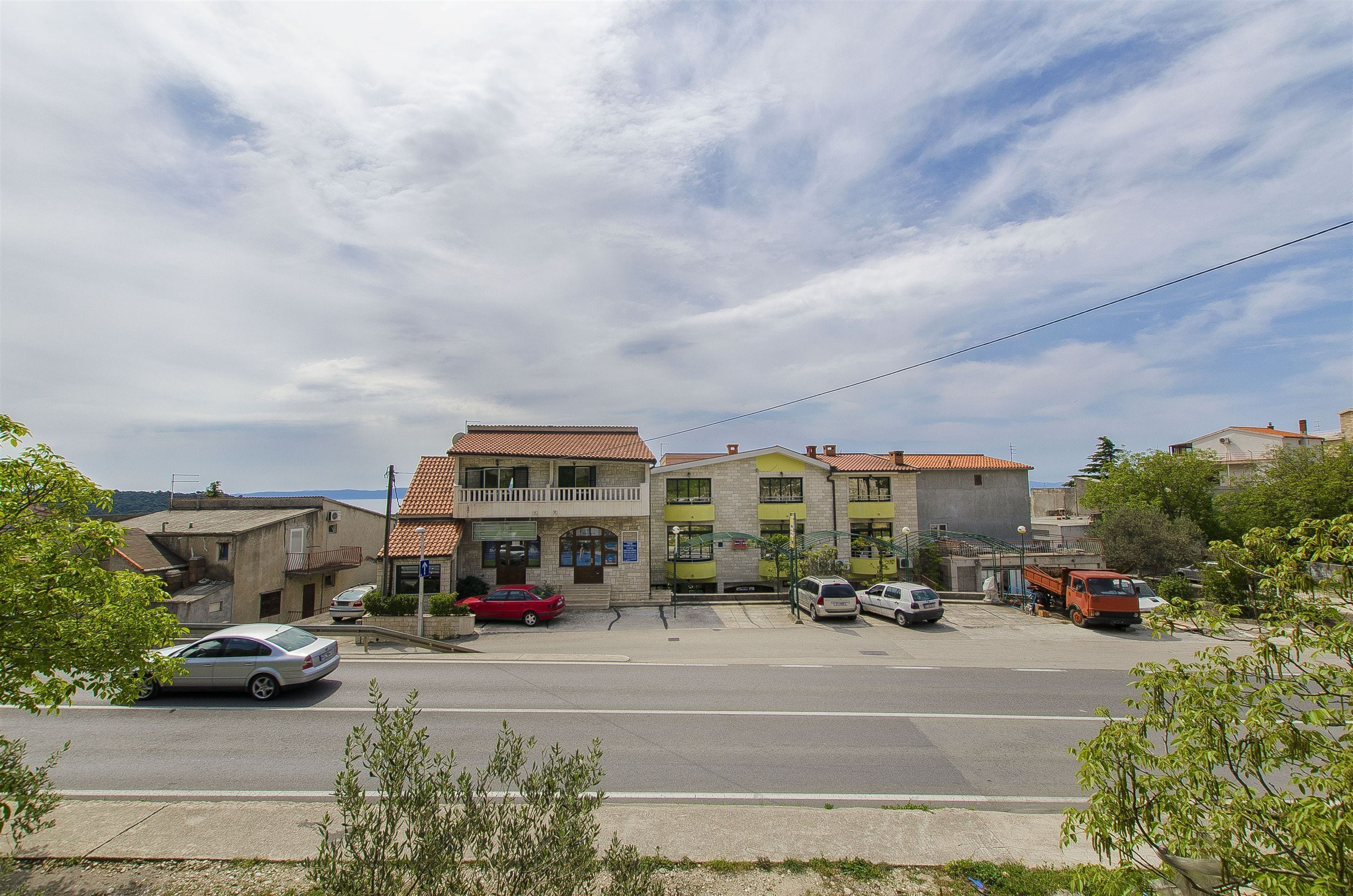 A street view with buildings, parked cars, and a clear sky.
