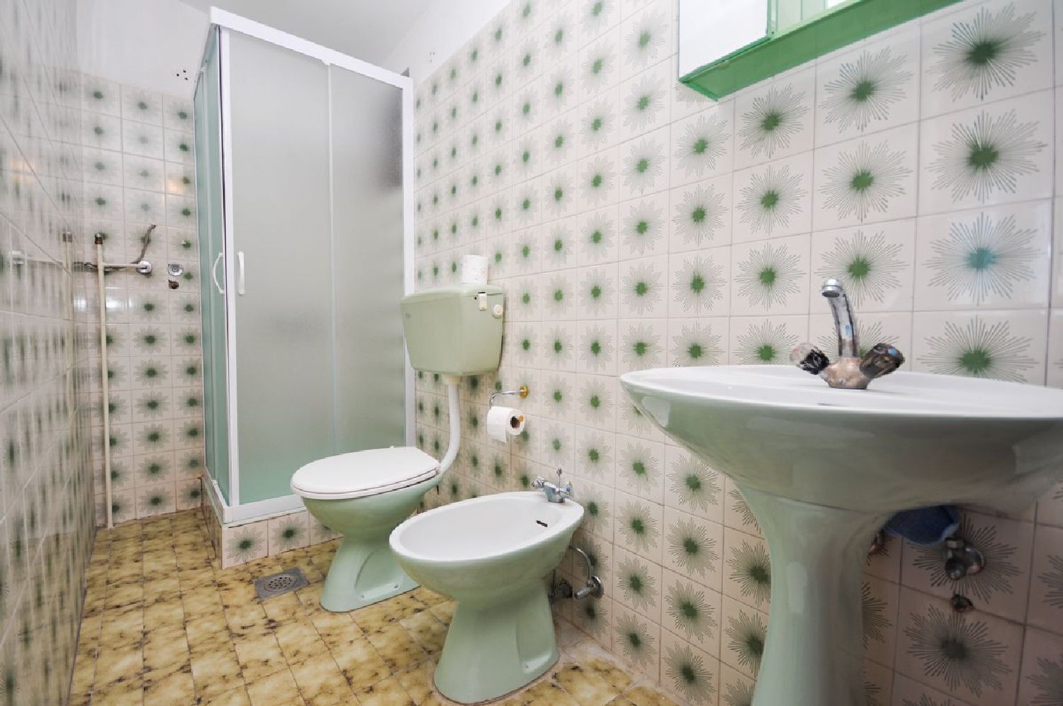 A bathroom with a toilet, bidet, and sink, all in a light color scheme.
