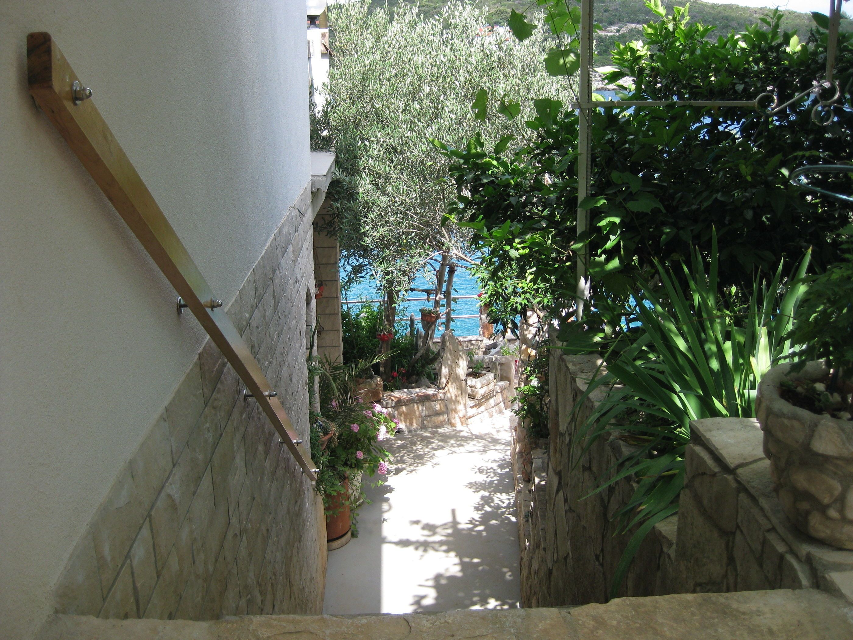 A narrow stone staircase leading to a balcony with a view of the sea.