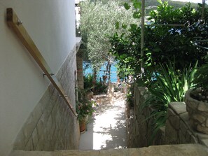 Un escalier étroit en pierre menant à un balcon d’où l’on peut admirer la mer.