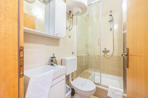 A modern bathroom with a glass shower enclosure, a bathtub, and a toilet.