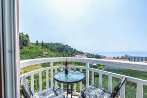 A balcony with a glass table, two wine glasses, and a bottle of wine.