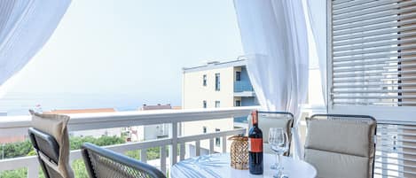 A balcony with a table, chairs, and a bottle of wine.