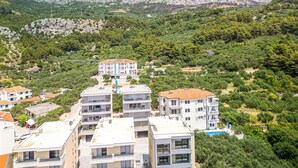 Zona residencial con modernos edificios de apartamentos, rodeada de exuberante vegetación y montañas al fondo.