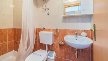 Et badeværelse med toilet, håndvask og bruser.