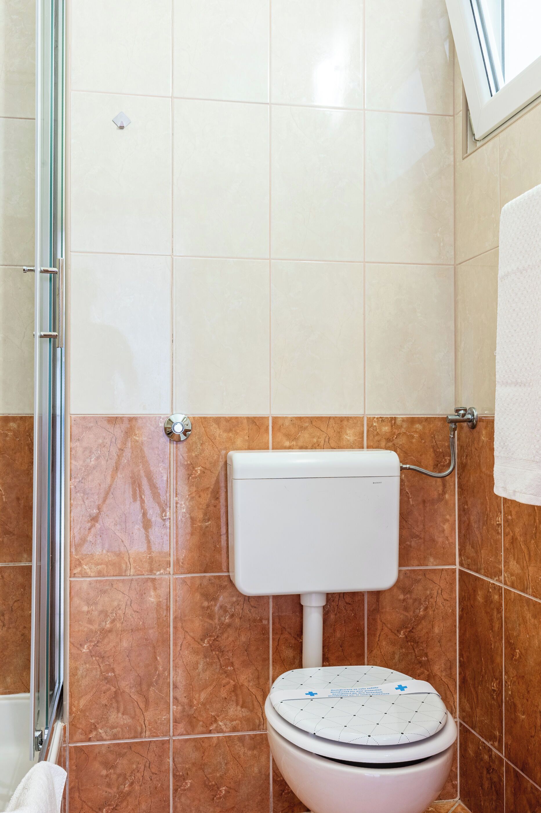 Un baño con inodoro, ducha y pared de azulejos.