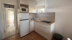 A compact kitchen with a microwave, sink, and wooden countertop. - Apartments Marija Jug (Primosten)