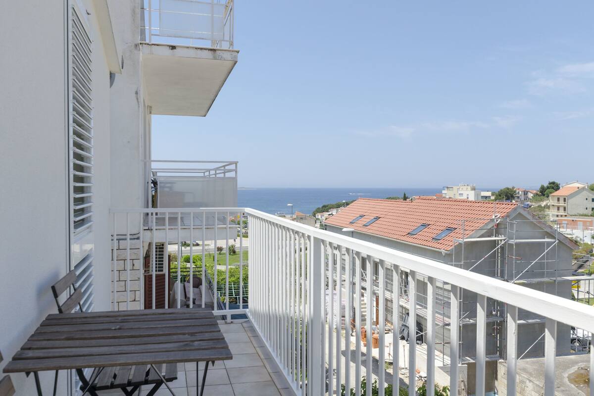 A balcony with a view of the sea and a building under construction.