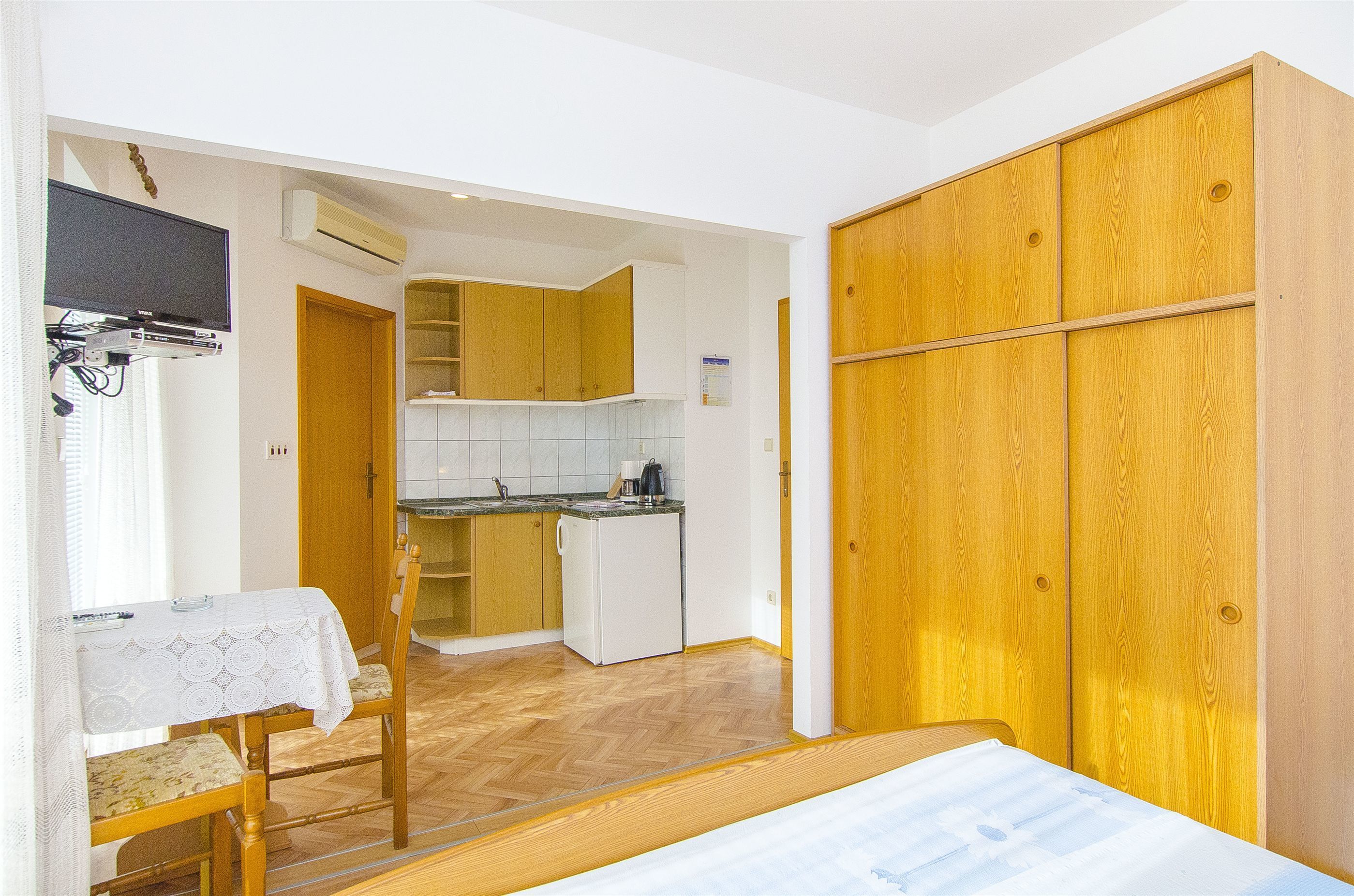 A compact room with a bed, a dining table, and a kitchenette.
