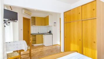 Una habitación funcional con cama, mesa de comedor y kitchenette.