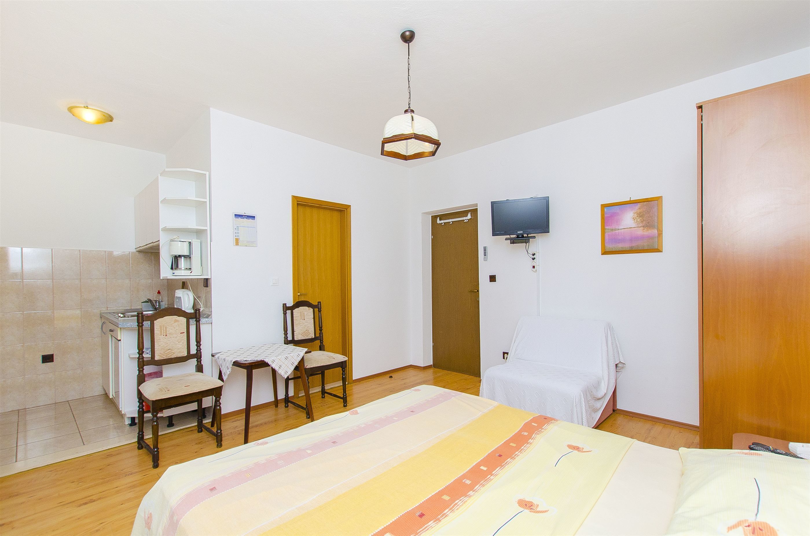 Une chambre d’hôtel comprenant un lit, un bureau avec une chaise, une télévision et une armoire en bois.