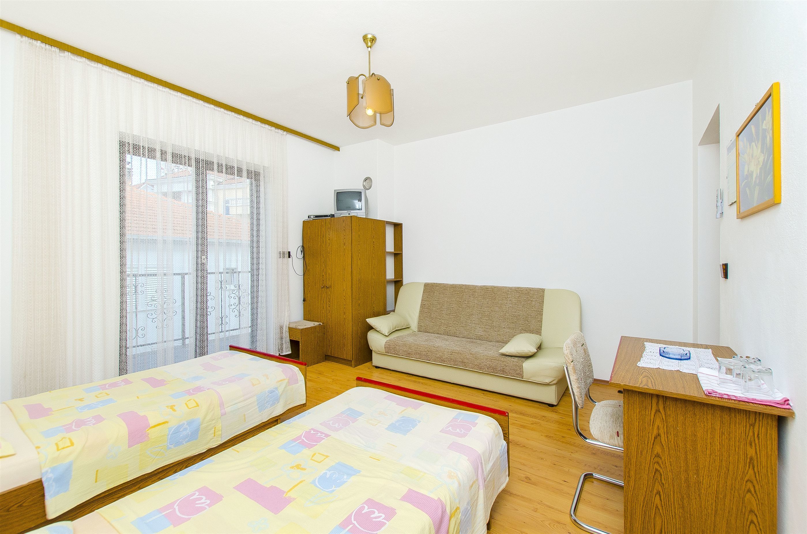 A room with two beds, a sofa, a desk, and a wardrobe.